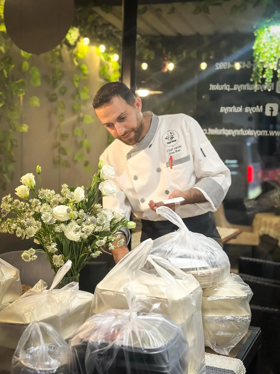 Chef-owner Diea Blan in his whites, preparing orders beside fresh flowers