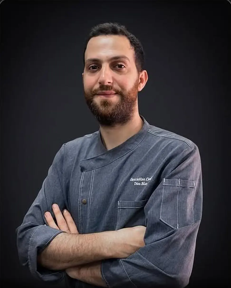 Chef Diea Blan, chef-owner of Moya Kuhnya, arms crossed in a grey chef jacket