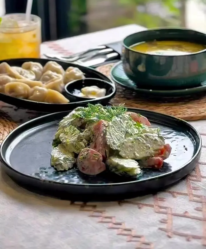 A table set with khinkali, soup and salad